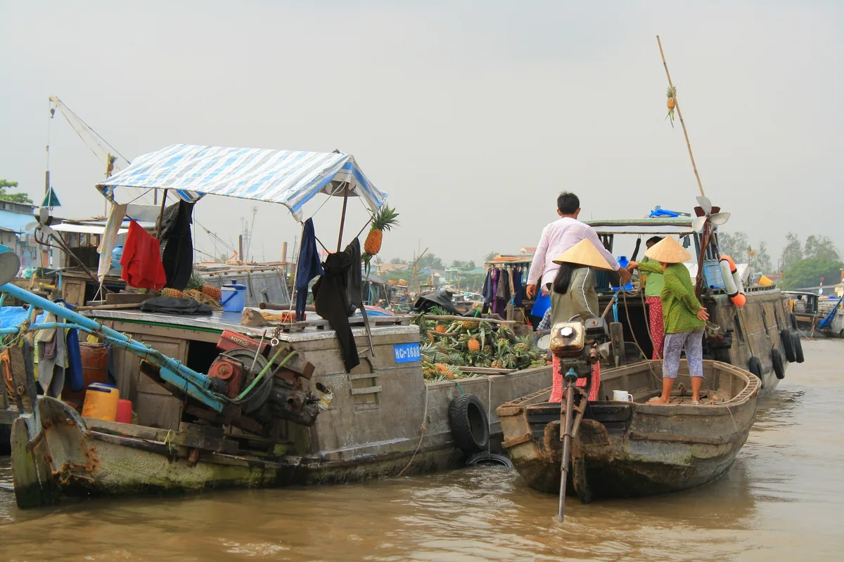 Người bán hàng trên các thuyền gỗ trao đổi trái cây tại chợ nổi Cái Răng gần Cần Thơ trên sông Mekong.