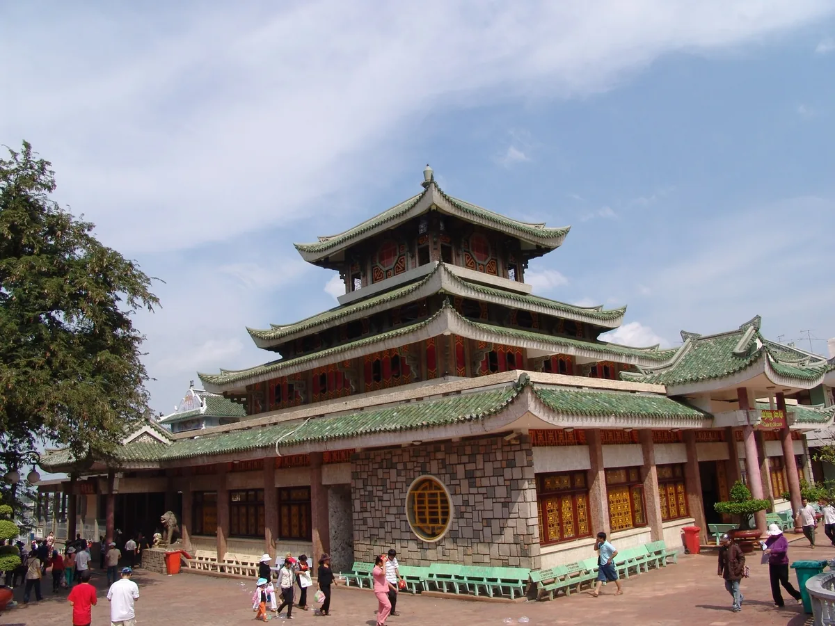 Ngôi chùa nhiều tầng mái ngói xanh với du khách dạo bước trong sân ở Châu Đốc.