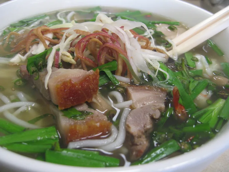 Một tô bún nước lèo với thịt heo, rau thơm và đôi đũa, món ăn đặc trưng miền Tây sông Mekong.