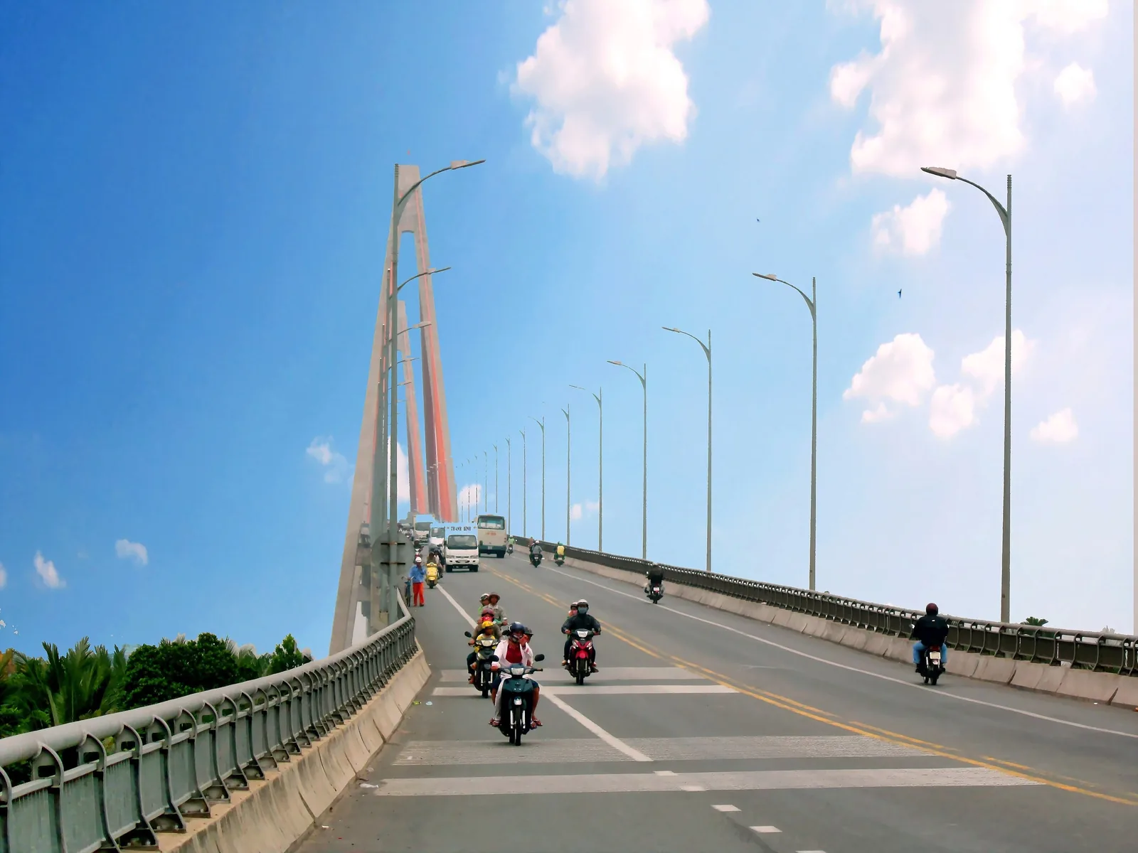 Xe máy và xe cộ qua cầu dây văng Rạch Miễu dưới bầu trời trong xanh ở đồng bằng sông Cửu Long.