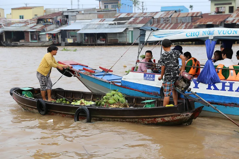 Thuyền bán trái cây nhỏ gặp thuyền du khách trên sông Mekong tại chợ nổi gần Cần Thơ.