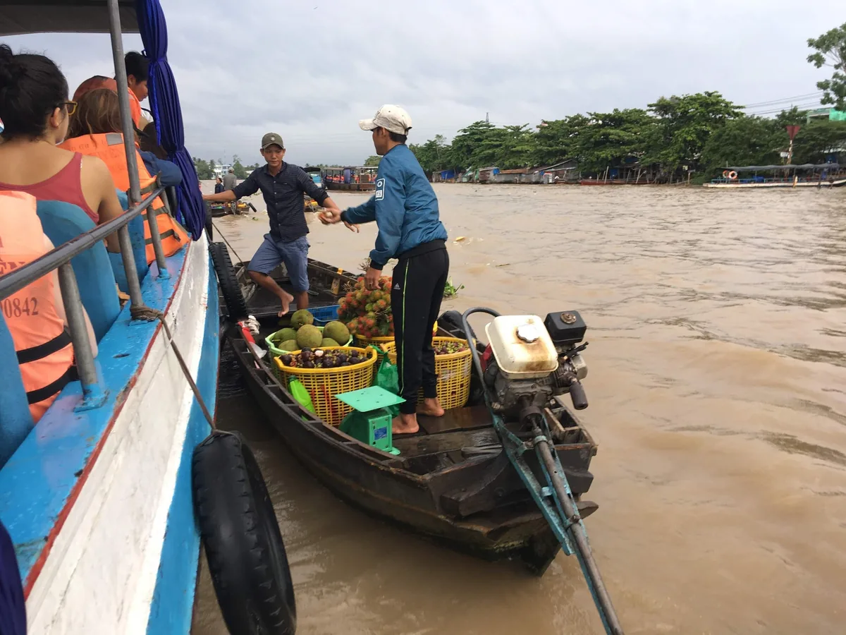 Người bán trái cây trên thuyền nhỏ bán hàng cho du khách ở chợ nổi Cái Răng, Cần Thơ.