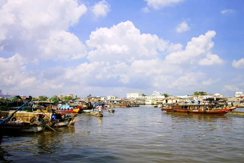 Những chiếc thuyền gỗ nổi trên sông rộng tại chợ nổi Cái Răng gần Cần Thơ dưới bầu trời trong xanh.