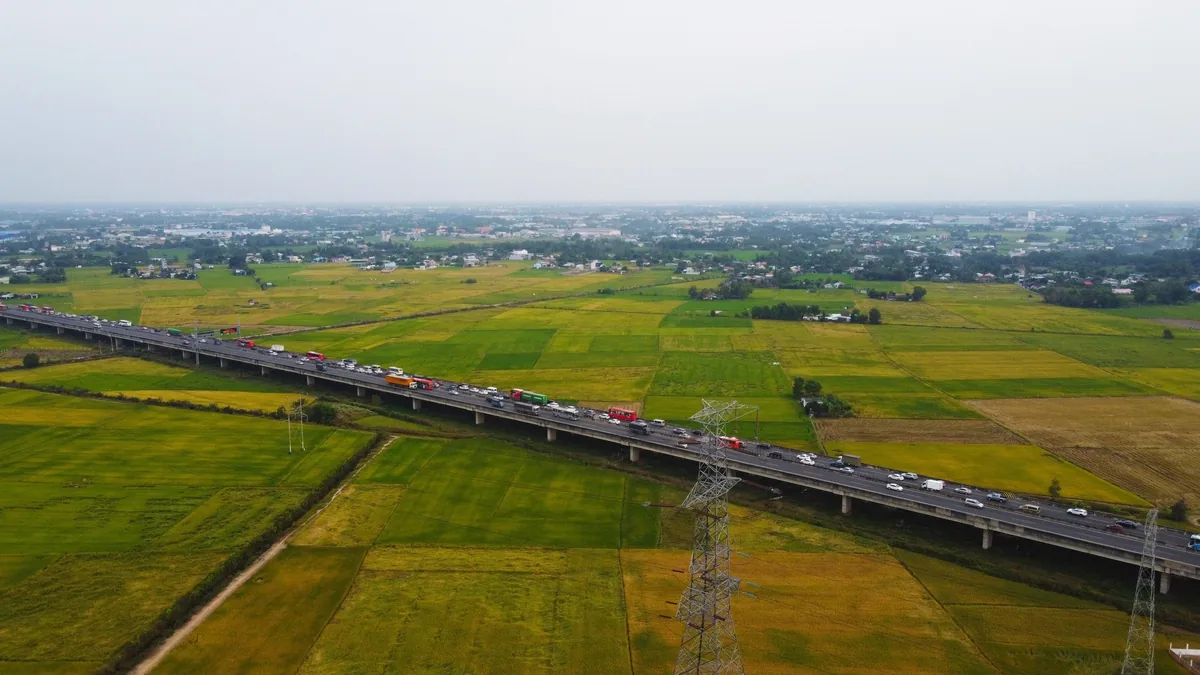 Góc nhìn từ trên cao cho thấy xe cộ trên đường cao tốc trên cao băng qua ruộng lúa ở đồng bằng sông Mekong.